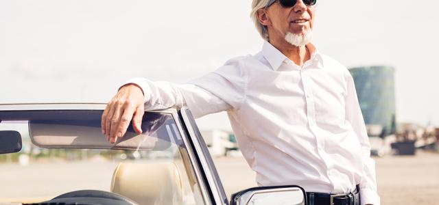 old man posing by car